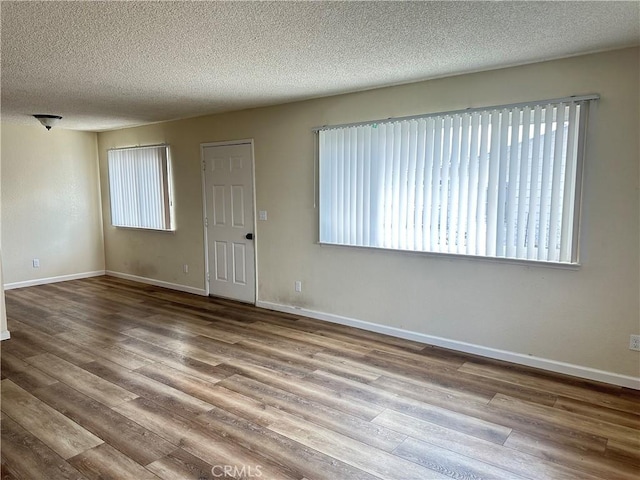 unfurnished room with hardwood / wood-style floors and a textured ceiling