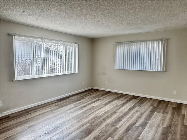 empty room featuring a textured ceiling and light hardwood / wood-style floors