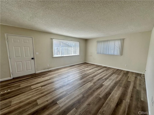 empty room with dark wood-type flooring and a textured ceiling