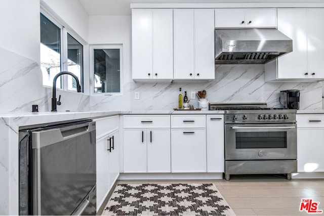 kitchen with white cabinetry, appliances with stainless steel finishes, and wall chimney range hood