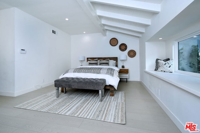 bedroom featuring vaulted ceiling with beams and light wood-type flooring