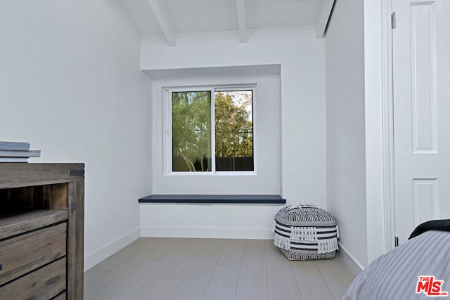 bedroom featuring beamed ceiling and light wood-type flooring