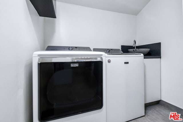 clothes washing area featuring sink, hardwood / wood-style floors, and washing machine and clothes dryer