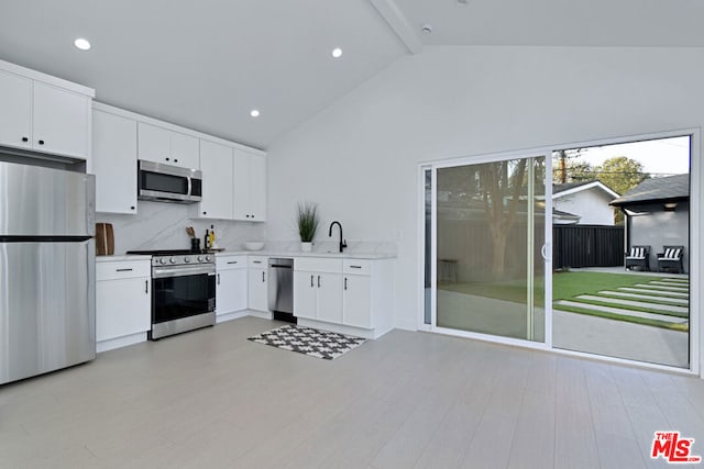 kitchen with stainless steel appliances, white cabinetry, light wood-type flooring, and beam ceiling