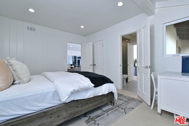 bedroom with ensuite bathroom and light hardwood / wood-style floors