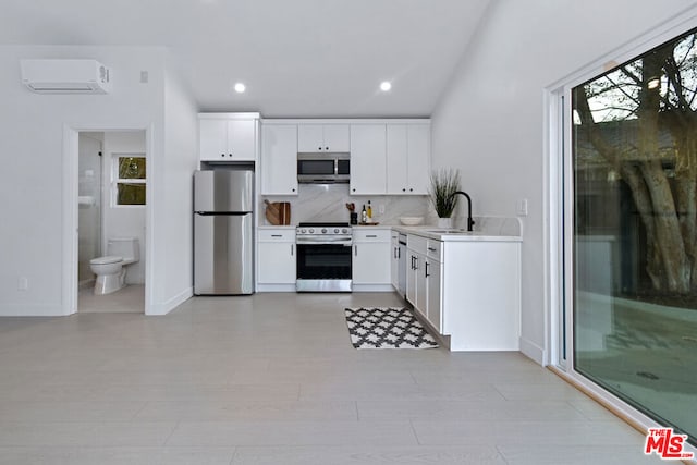 kitchen with white cabinetry, appliances with stainless steel finishes, sink, and an AC wall unit