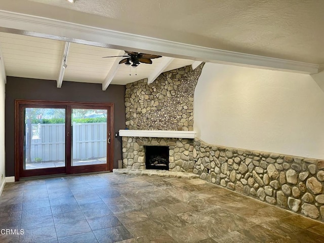 unfurnished living room featuring ceiling fan, a stone fireplace, wooden ceiling, and beamed ceiling