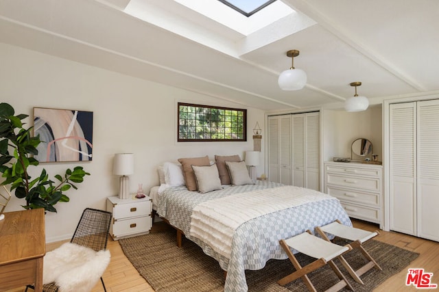 bedroom featuring lofted ceiling with skylight, multiple closets, and light wood-type flooring