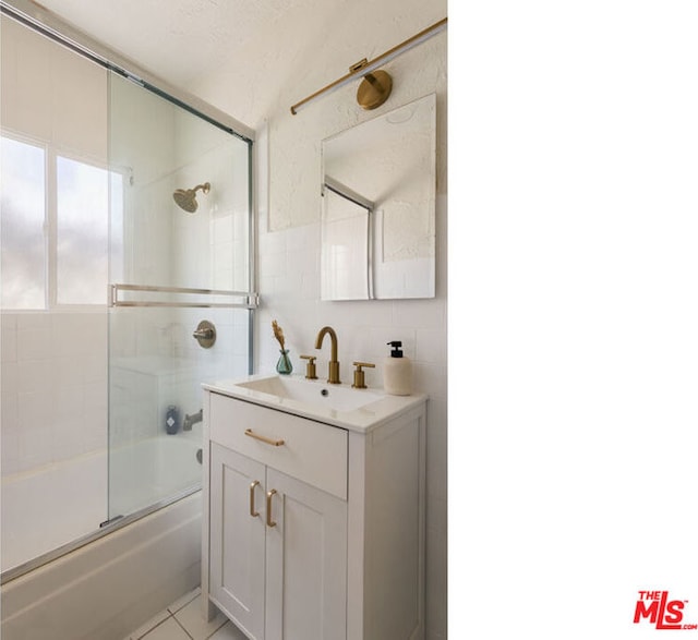 bathroom with tasteful backsplash, vanity, tile walls, and shower / bath combination with glass door