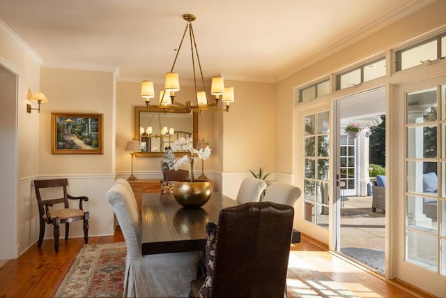 dining space with crown molding, hardwood / wood-style floors, a chandelier, and french doors