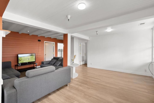 living room with beam ceiling, light wood-type flooring, and wood walls