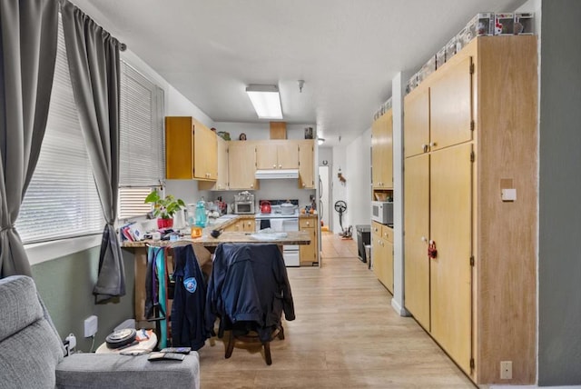 kitchen with light brown cabinetry, light wood-type flooring, a kitchen breakfast bar, kitchen peninsula, and white appliances