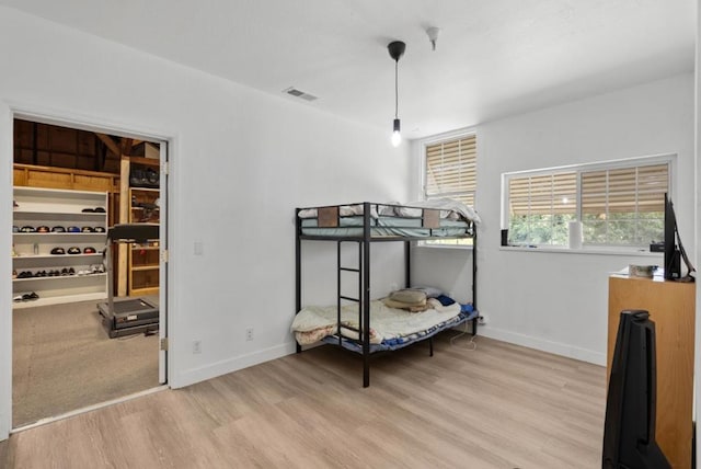 bedroom featuring a spacious closet and light hardwood / wood-style floors