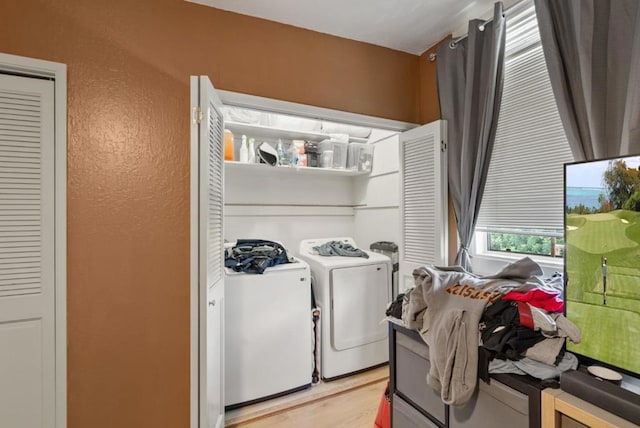 clothes washing area with independent washer and dryer and light wood-type flooring