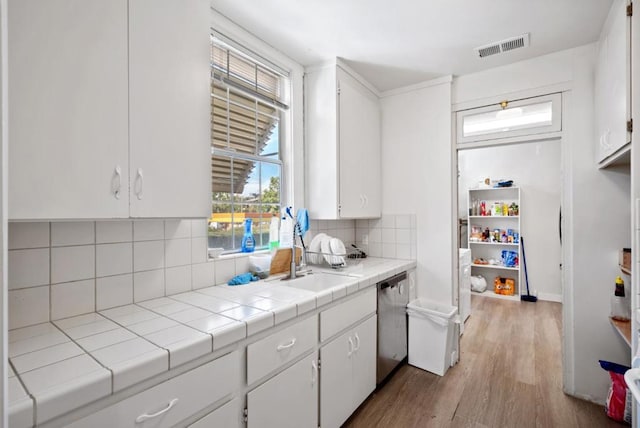 kitchen featuring tasteful backsplash, tile counters, dishwasher, and white cabinets