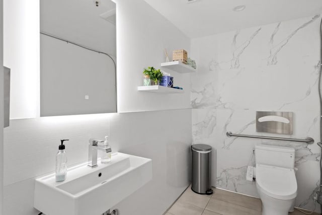 bathroom with sink, tile walls, tile patterned floors, and toilet