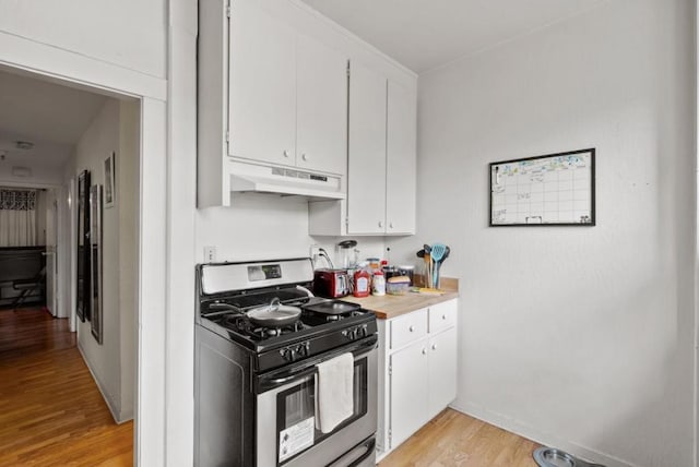 kitchen with white cabinets, light wood-type flooring, and stainless steel gas range oven