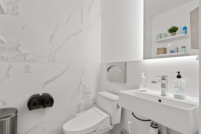 bathroom featuring tile walls, sink, and toilet