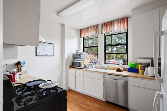 kitchen featuring stainless steel appliances, sink, light hardwood / wood-style flooring, and white cabinets