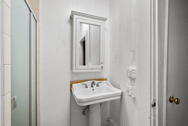 bathroom with a shower with door and sink