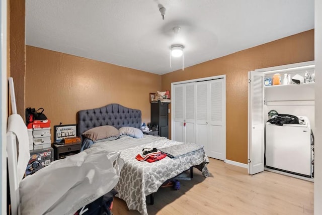 bedroom with washer / clothes dryer, ceiling fan, light wood-type flooring, and a closet