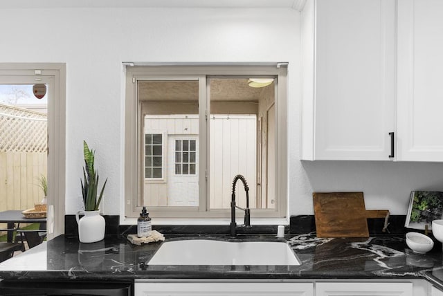 kitchen featuring sink, white cabinets, and dark stone counters