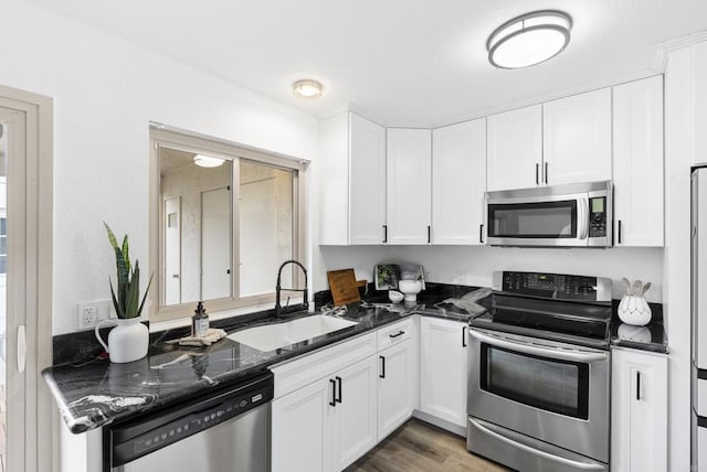 kitchen featuring white cabinetry, sink, stainless steel appliances, and dark stone countertops