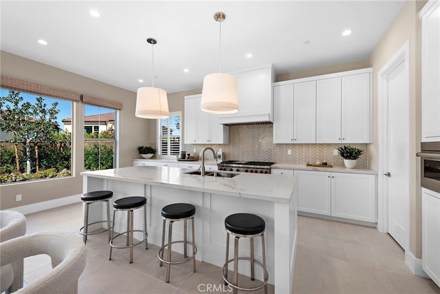 kitchen featuring pendant lighting, sink, white cabinets, and a center island with sink