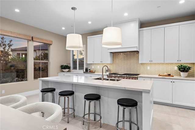 kitchen featuring pendant lighting, sink, white cabinetry, and a kitchen island with sink