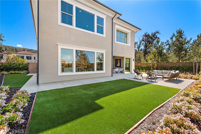 back of property with a lawn, outdoor lounge area, and a patio