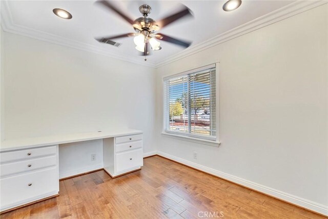 unfurnished office with ceiling fan, ornamental molding, built in desk, and light hardwood / wood-style flooring