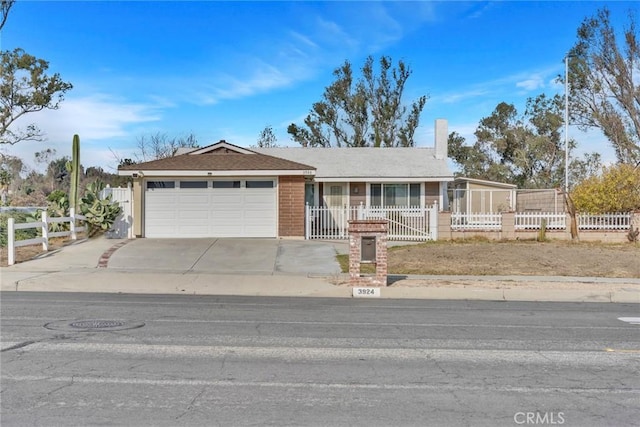 single story home featuring an attached garage, brick siding, fence, concrete driveway, and a chimney