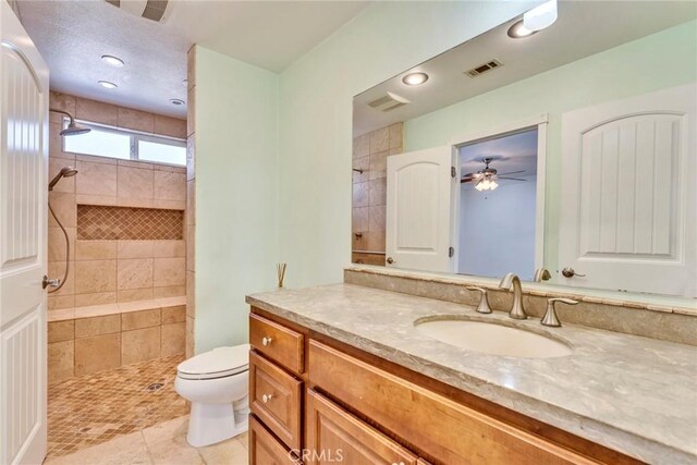 bathroom featuring vanity, tile patterned flooring, toilet, and tiled shower