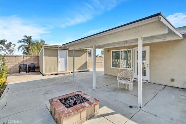 view of patio / terrace featuring an outdoor fire pit and a storage unit