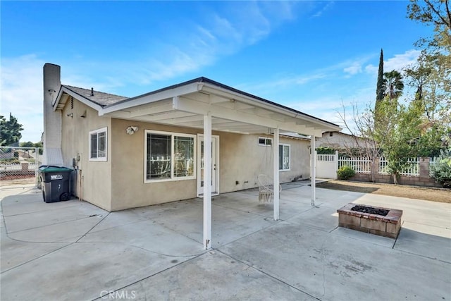 rear view of house featuring a patio area, fence, a fire pit, and stucco siding