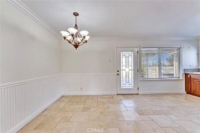 interior space with a chandelier, stone finish flooring, ornamental molding, and wainscoting