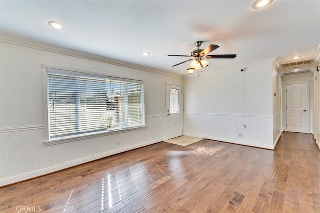 spare room with a wainscoted wall, crown molding, and wood finished floors