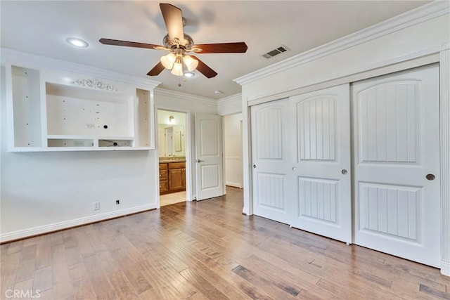 unfurnished bedroom featuring crown molding, light hardwood / wood-style floors, a closet, and ceiling fan