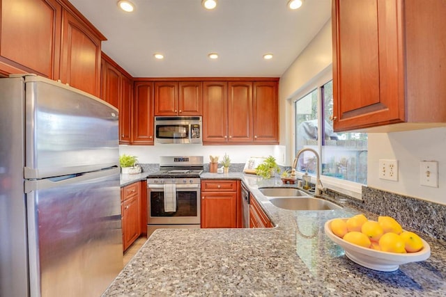 kitchen with light stone counters, stainless steel appliances, and sink