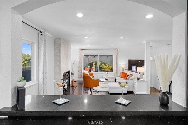 interior space featuring ornamental molding, decorative columns, and dark stone counters