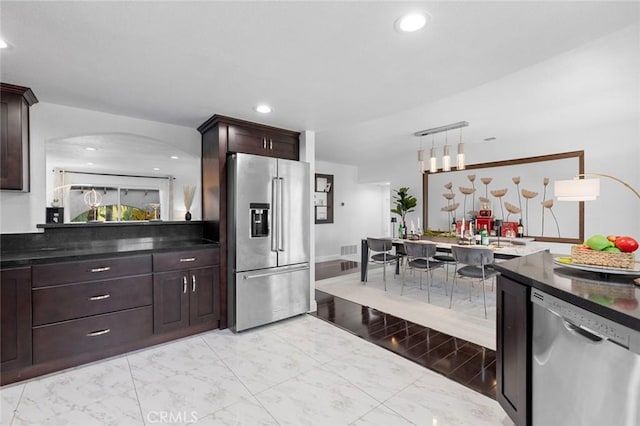 kitchen featuring pendant lighting, stainless steel appliances, and dark brown cabinets