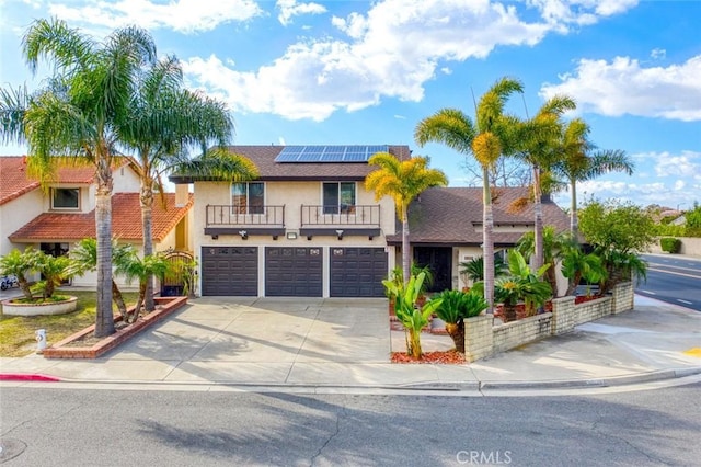 view of front of home with a garage, a balcony, and solar panels