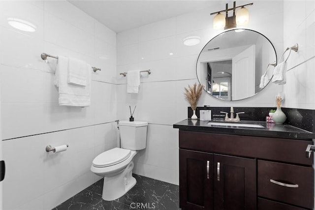 bathroom featuring tile walls, vanity, and toilet