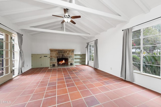 unfurnished living room featuring a stone fireplace, lofted ceiling with beams, tile patterned floors, and ceiling fan