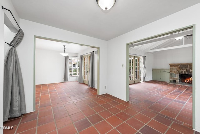 empty room with french doors, a fireplace, and tile patterned flooring