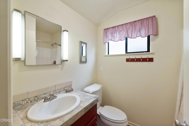 bathroom featuring vanity, lofted ceiling, walk in shower, and toilet