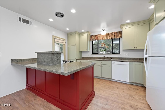 kitchen with white appliances, a breakfast bar, kitchen peninsula, dark stone counters, and light wood-type flooring