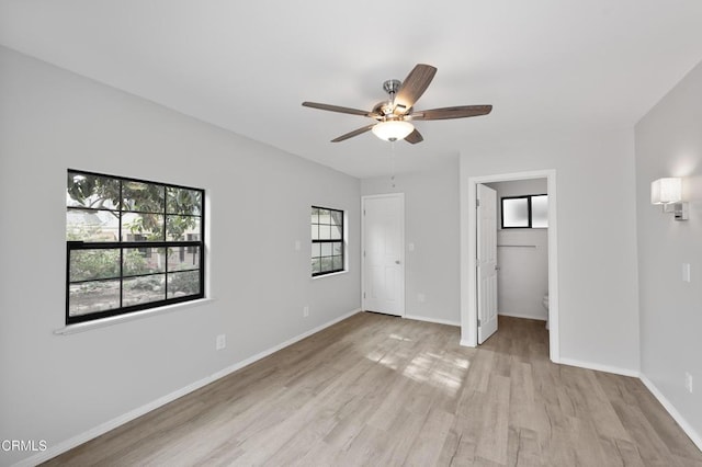 unfurnished bedroom featuring ceiling fan, a spacious closet, and light hardwood / wood-style floors