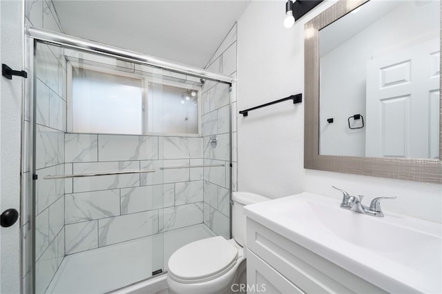 bathroom with vanity, a shower with shower door, and toilet