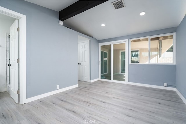 empty room featuring lofted ceiling with beams and light hardwood / wood-style floors